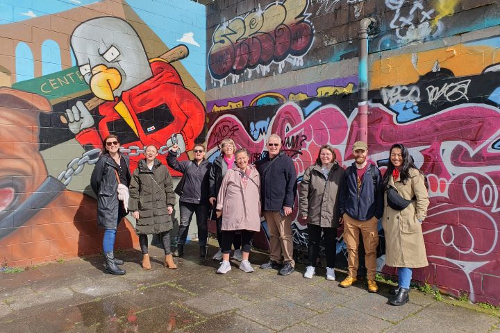 a group of people standing in front of a graffiti covered wall