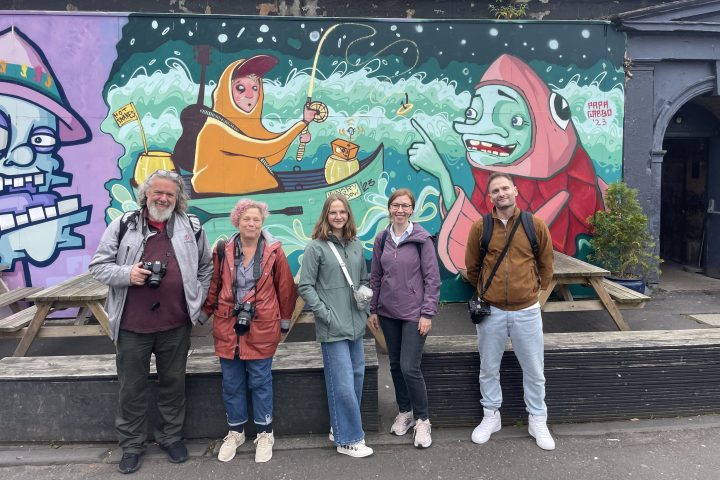 a group of people standing in front of a graffiti covered wall