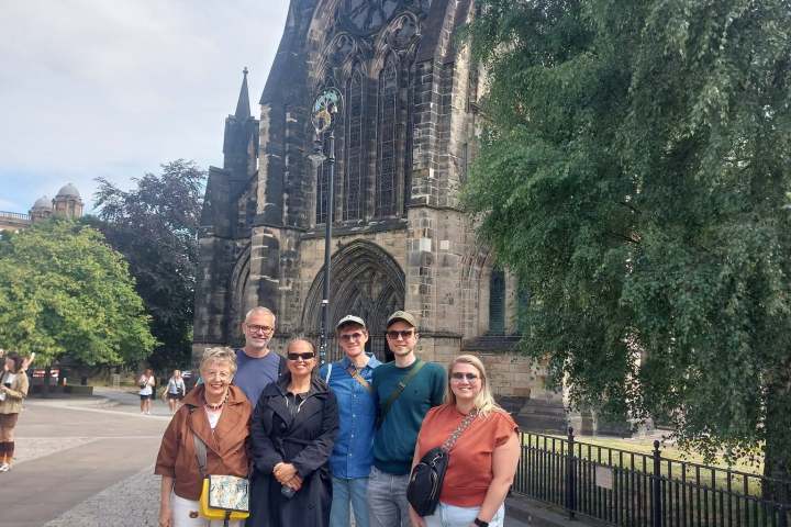Group of people posing in front of a large historic church on a sunny day.