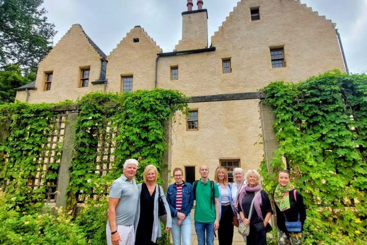 Group of people posing in front of ivy-covered historic building.