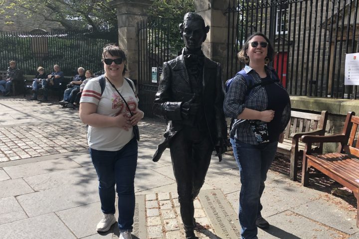 a group of people on a sidewalk near a fence