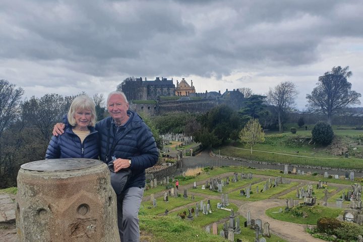 a man standing next to a stone wall