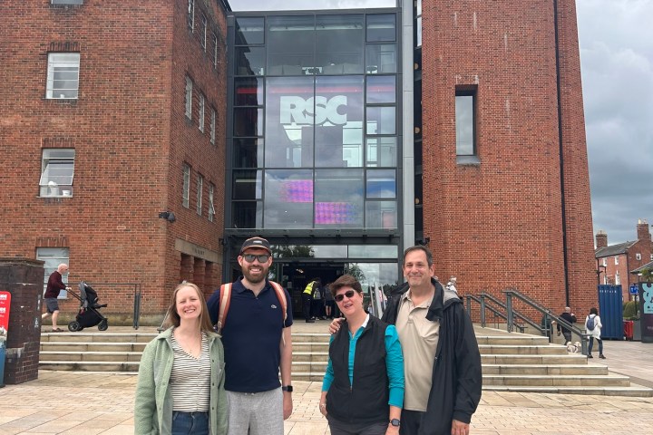 Four people standing in front of the RSC building with brick facade and glass entrance.