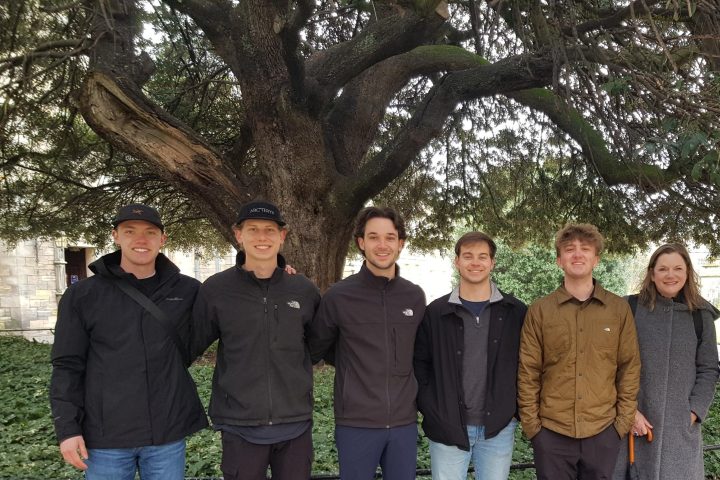 a group of people standing in front of a tree posing for the camera