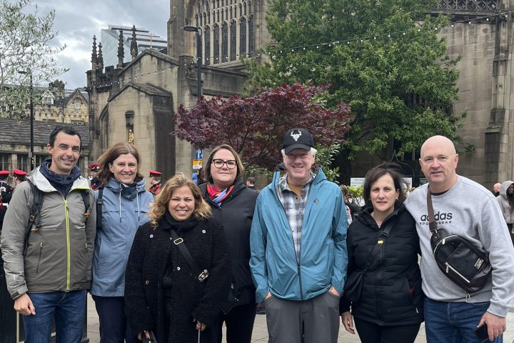 Group of people pose in front of a historic cathedral with cloudy sky.