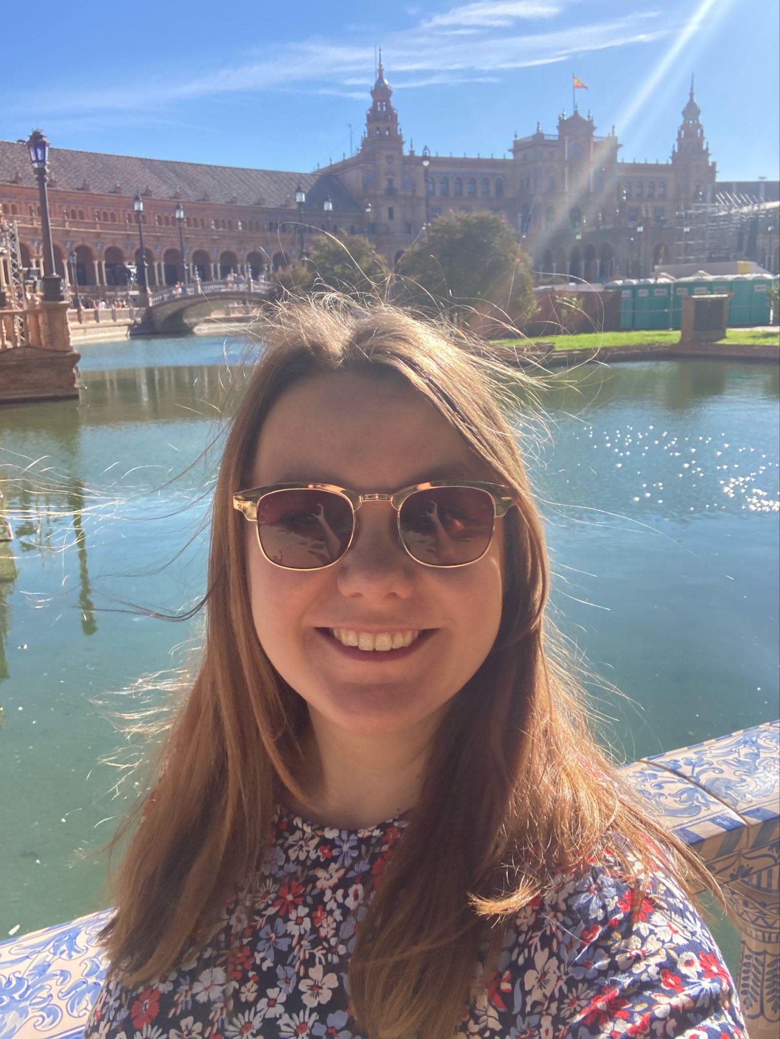 a woman wearing sunglasses and smiling next to a body of water