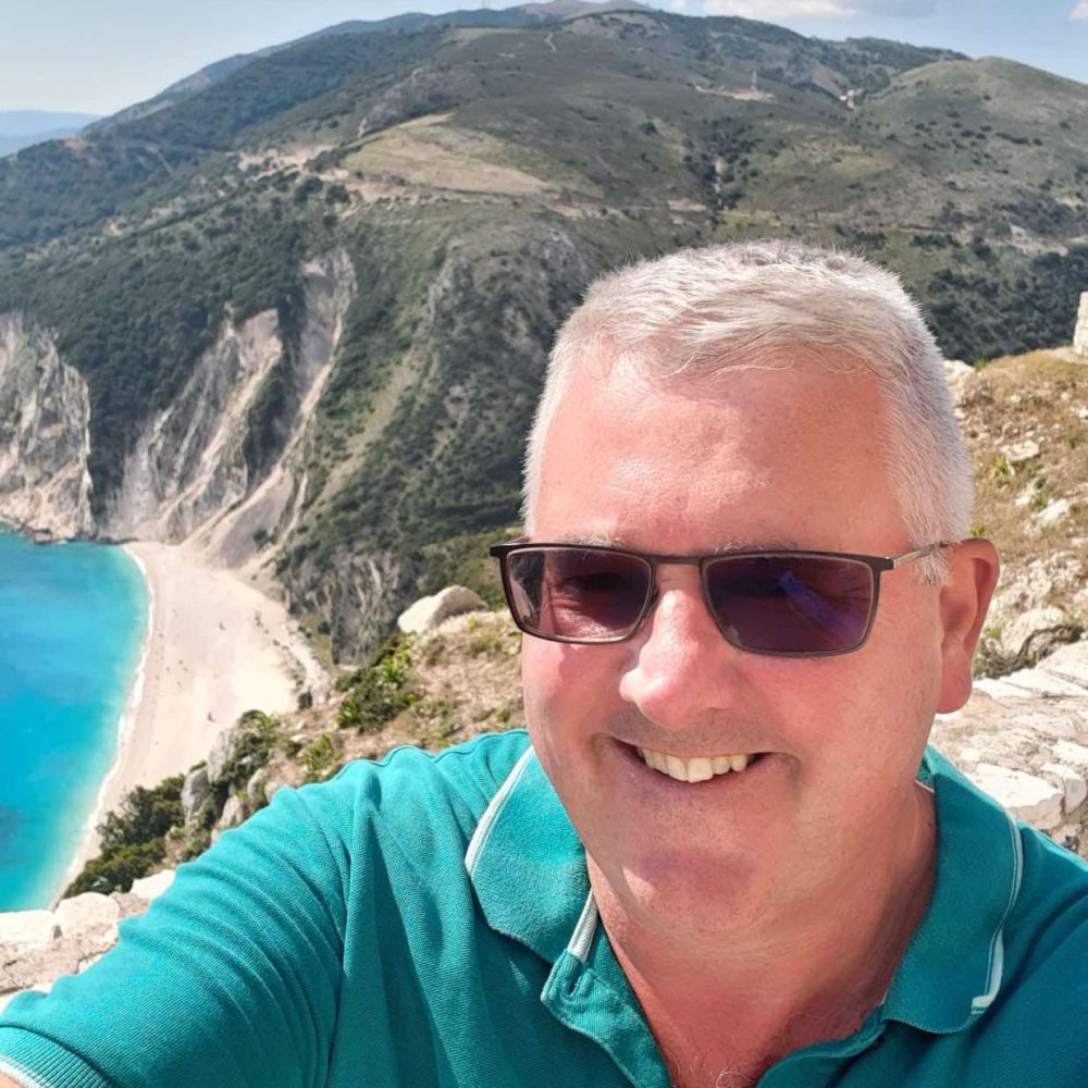 a man wearing sunglasses with a mountain in the background