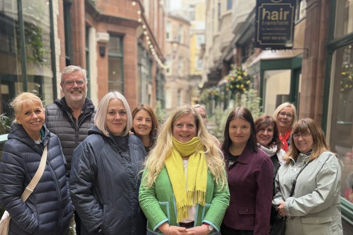 Group of nine people smiling in a narrow street with historic buildings.