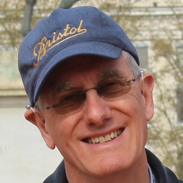 Smiling person wearing glasses and a blue cap with 'Bristol' written on it.