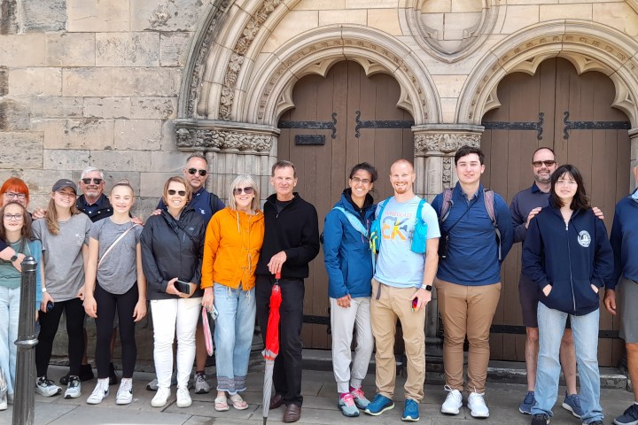Group of people posing in front of an ornate, arched stone doorway.