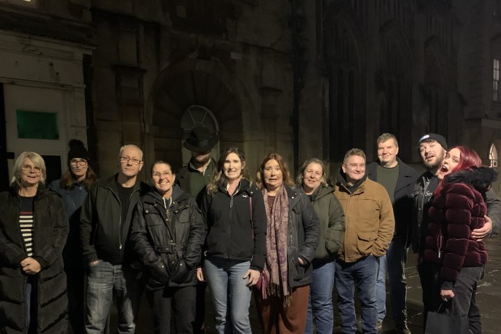 Group of people posing together on a stone street at night.