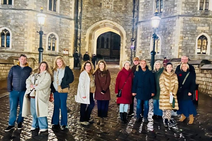 Group of people posing at night in front of a lit-up historic castle entrance.