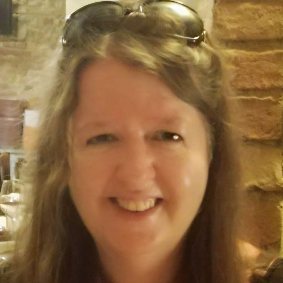 Smiling person in a restaurant with sunglasses on head.