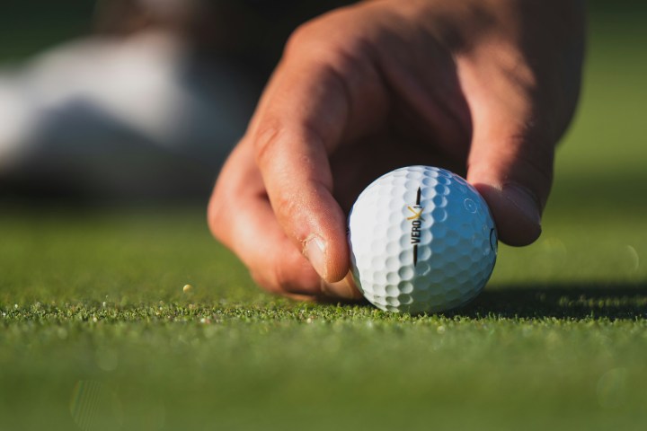 Hand placing a golf ball on the grass, close-up.
