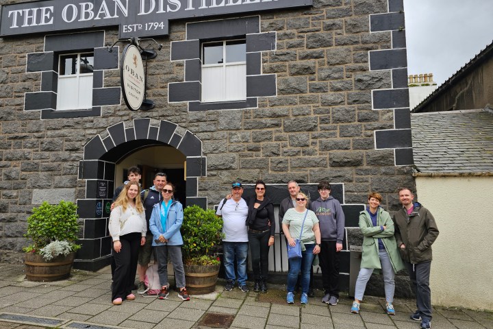 Group of people standing in front of The Oban Distillery entrance.