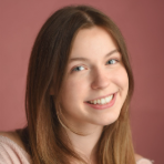Smiling person with long brown hair against a pink background.